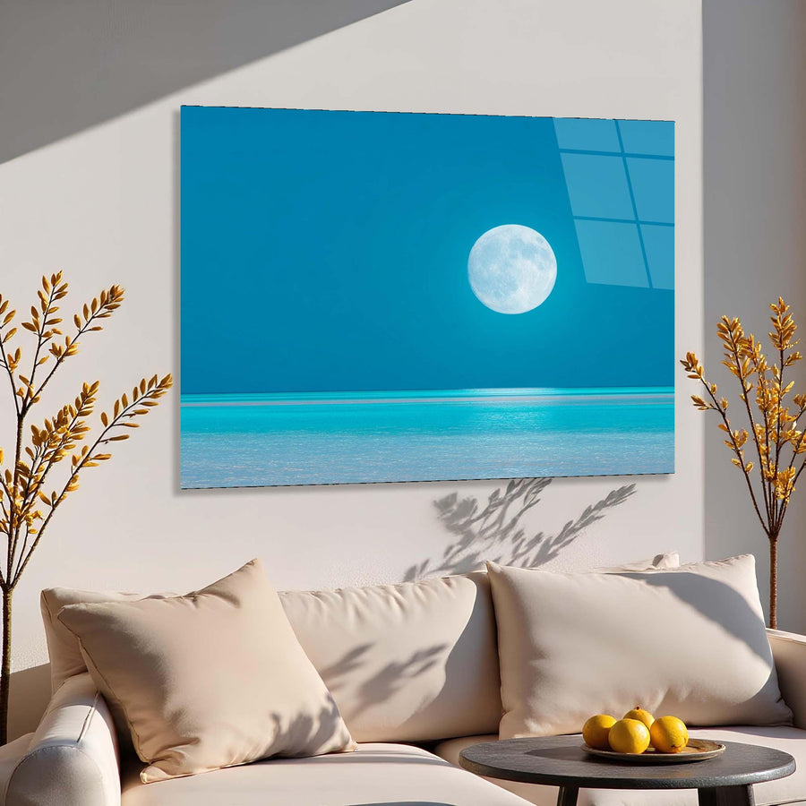 Sofa with decorative pillows and a small table with fruits, featuring a large wall art of a beach scene with a moon.