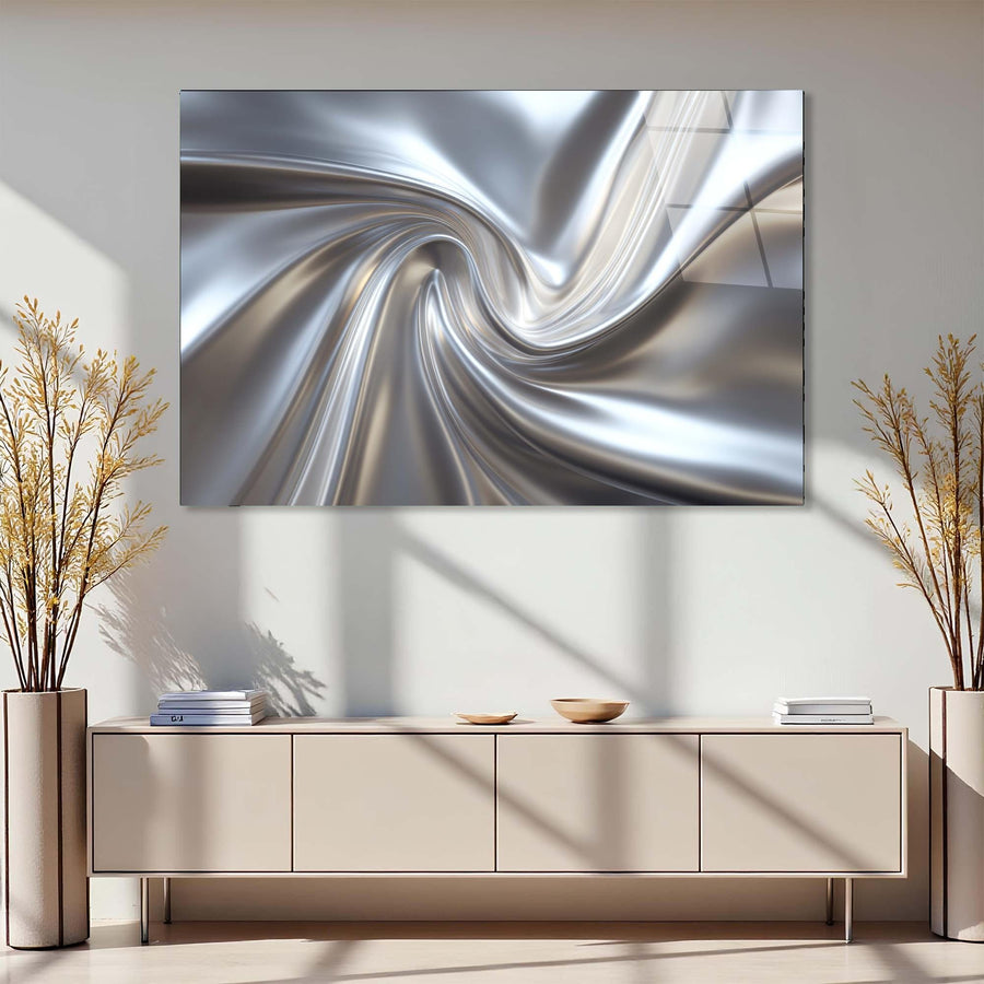 Abstract silver spiral artwork on a wall above a light-colored cabinet with decorative plants.