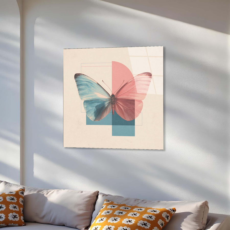 Framed artwork of a butterfly with pink and blue wings on a white wall above a sofa.