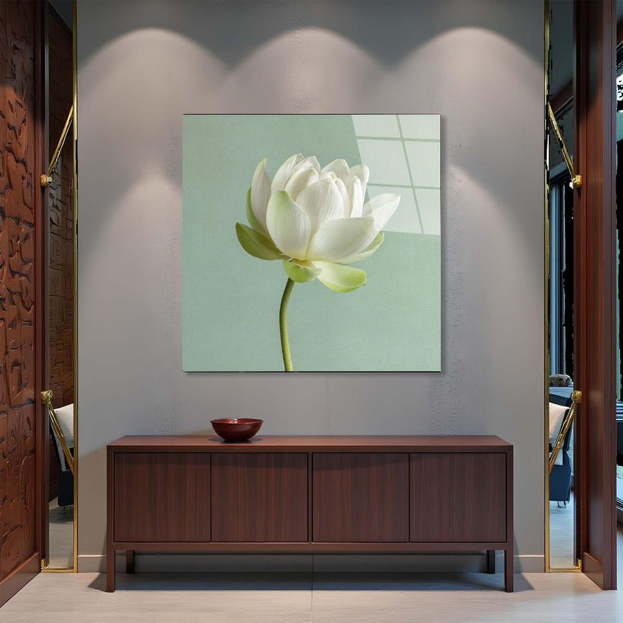 White lotus flower painting on a wall above a wooden cabinet.