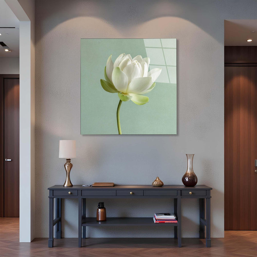 Framed artwork of a white flower on a wall above a dark wooden console table with decorative items.