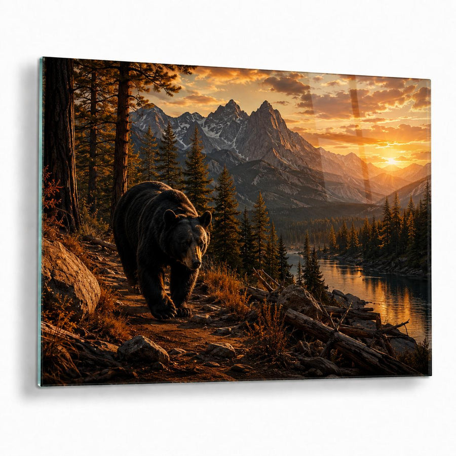 A rectangular wall art print or canvas showing a bear walking along a forest path toward mountains, a lake, and a glowing sunset. The artwork is photographed against a plain white background with a slight shadow.