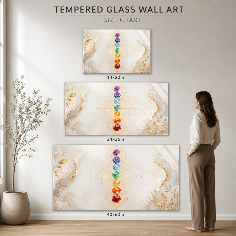Three framed canvas wall art prints with a vertical rainbow chakra design on an abstract cream and gold marble background, shown on a wall with size labels 14x20in, 24x36in, and 40x60in. A woman stands to the right for scale, and a potted plant is on the left.