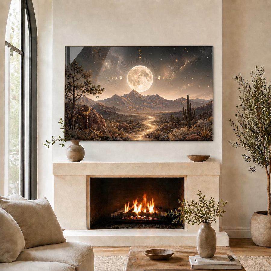A large rectangular wall art print depicting a desert mountain landscape with a glowing full moon, stars, and a winding path, displayed above a fireplace in a styled living room with a sofa, vases, and potted plants.