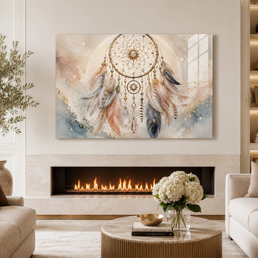 A large rectangular wall art print showing a dreamcatcher with soft pastel watercolor background, displayed above a fireplace in a styled living room with a sofa, coffee table, flowers, and greenery.