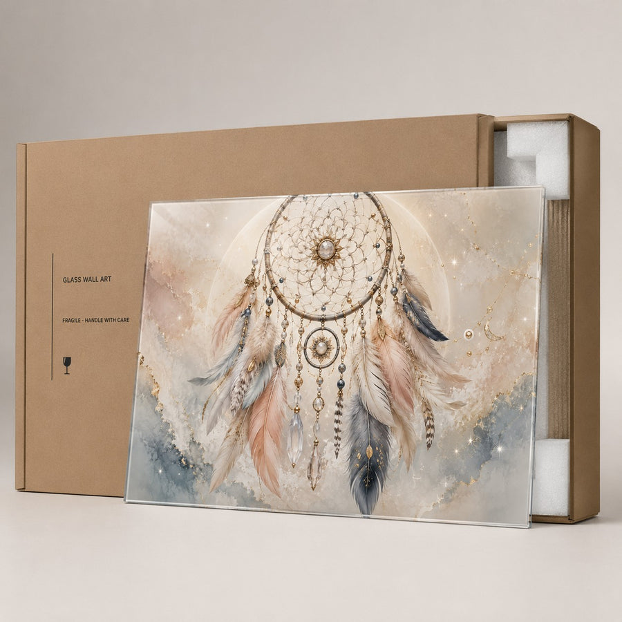 A framed glass wall art print featuring a dreamcatcher with feathers in soft beige, blush, gray, and blue tones, displayed in front of a brown kraft box on a light neutral background.