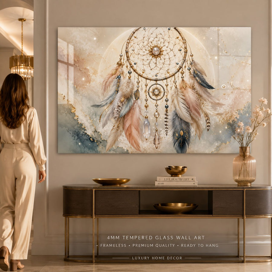 A large framed wall art print featuring a dreamcatcher with soft pastel feathers and glowing circular details, displayed above a console table in a modern interior. A woman is partially visible on the left, and the artwork includes text at the bottom describing 4mm tempered glass wall art.
